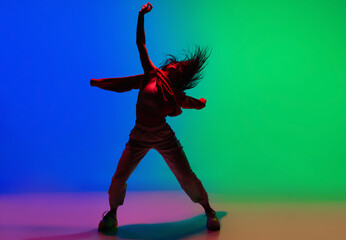 Inspiration. Stylish sportive girl dancing hip-hop in stylish clothes on colorful background at...