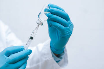 Doctor, nurse, scientist hand in blue gloves holding flu, measles, coronavirus, covid-19 vaccine...
