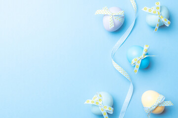 Easter background. Colorful egg with tape ribbon on pastel blue background in Happy Easter decoration. Spring holiday top view concept.