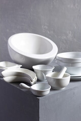 Empty crockery or ceramic dishes set. Kitchen dishware and tableware on grey near wall background