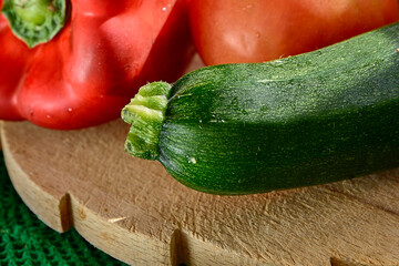 Red pepper, zucchini and tomato in detail on wooden table.
