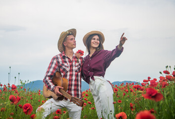 Lovely evening. romantic couple with guitar in poppy flowers. family summer vacation. happy man and woman in love enjoy spring weather. happy relations. girl and guy in field. music