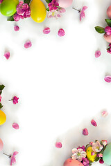 Easter decoration. Easter frame of pink flowers apple tree, colored easter eggs on white background with space for text. Top view, flat lay