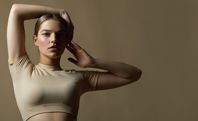 Beautiful young woman with natural makeup and gathered hair, dressed in a gray sports uniform, posing in the studio on a gray background.