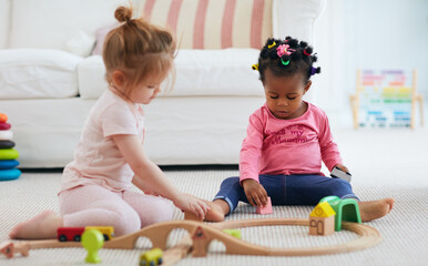 cute toddler baby girls playing toys together on the carpet