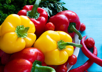 Fresh large yellow and red peppers on a white plate on a blue background