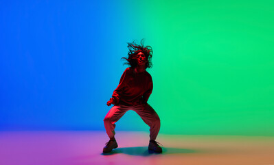 Street. Stylish sportive girl dancing hip-hop in stylish clothes on colorful background at dance hall in neon light. Youth culture, movement, style and fashion, action. Fashionable bright portrait.