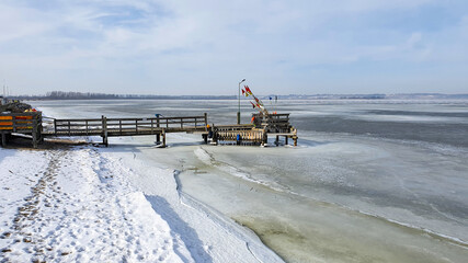 A short wooden pier on the shore of the frozen sea