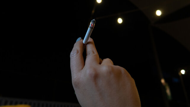 Mano de mujer con cigarrillo encendido en la mano