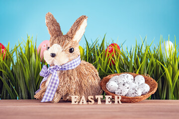 Easter eggs and cute bunny on wood table with green grass. Festive decoration