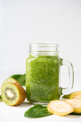 Vegan green smoothie in a jar with spinach, banana and kiwi on a white background