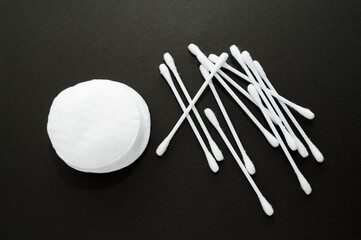 Close-up of cotton pad and cotton swabs. Top view from above. Black background.
