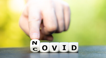 Symbol for wipe out covid 19. Hand turns dice and changes the expression "covid" to "novid" (no covid).