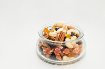 Nuts, candied fruits, dried berries in a glass bowl. Healthy vegeterian food. Cashews, Brazil nuts, raisins.