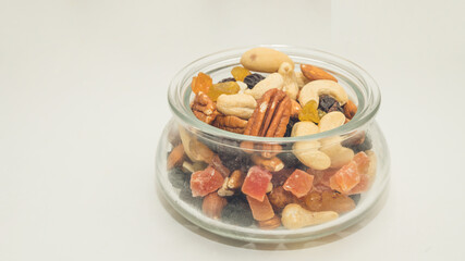 Nuts, candied fruits, dried berries in a glass bowl. Healthy vegeterian food. Cashews, Brazil nuts, raisins.