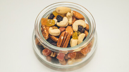 Nuts, candied fruits, dried berries in a glass bowl. Healthy vegeterian food. Cashews, Brazil nuts, raisins.