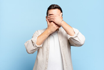 handsome adult blond man covering face with both hands saying no to the camera! refusing pictures...