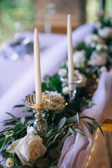 Amazing decoration of the wedding table with flowers, white fabrics, candles on the tables.