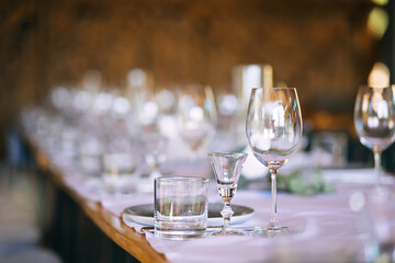 Wedding decor, glasses for wine and champagne on the table. Plates, cutlery. White tablecloth.