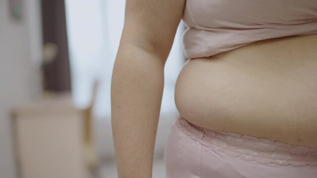 Oversize woman showing side folds, loosing belly fat, abdominal obesity, diet