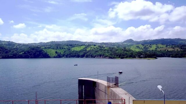 aerial view slowly zooms in at dum with large blue lake and many small speedboats
