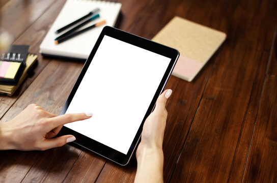Mockup image of a woman using digital tablet with blank screen on wooden table. Close up photo of female hands holding device vertically