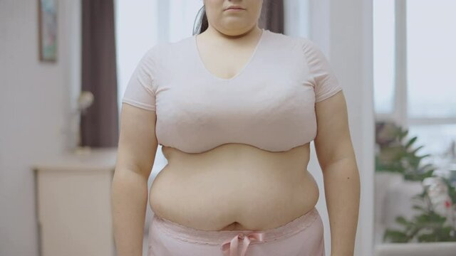 Sad obese woman holding side folds, putting on weight, eating disorder, calories