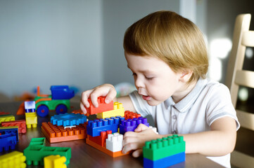 Cute preschooler little boy playing with construction toy blocks building a tower. Child and toys. 