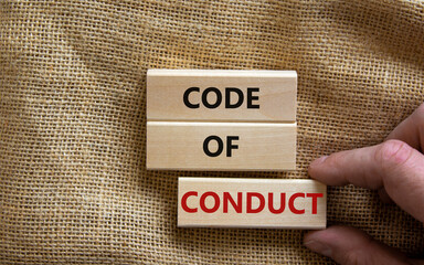 Code of conduct symbol. Concept words 'Code of conduct' on wooden blocks on a beautiful canvas background. Businessman hand. Business and code of conduct concept. Copy space.