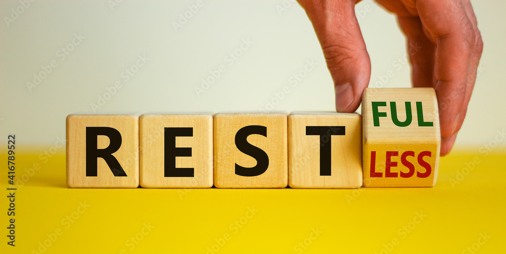 Fototapete restless or restful symbol. businessman turns the wooden cube, changes the word 'restless' to 'restf