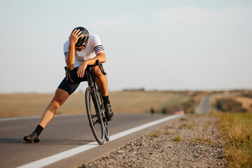 Exhausted cyclist relaxing on road after long riding