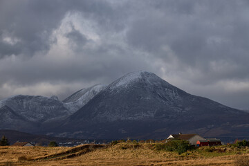 Naklejka premium rural scene, yellow oval with cottage and snowy mountains in winter. concept travel, tourism, mountain