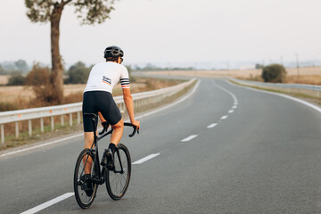 Back view of active man riding bike on fresh air