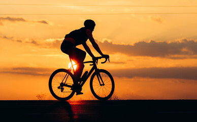 Fototapeta na wymiar Silhouette of active cyclist riding bike during sunset