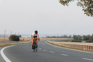 Muscular man riding bike with high speed on road