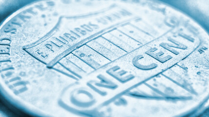 American 1 one cent coin very close up. Light blue tinted background or wallpaper on an economic, financial, banking theme. USA money backdrop. State benefits and government assistance. Strong macro