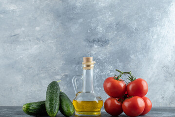 Cucumbers and tomatoes with fresh olive oil on grey background