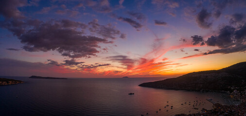 Aerial panorama drone shot of sunset burning sky clouds on Komiza town over Vis Island in Croatia Summer