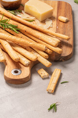 Traditional italian breadsticks grissini with rosemary, parmesan cheese, olive oil, garlic and salt on a gray background.