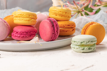 Colorful french macaroon cakes. Macaroons with jasmine flowers on white table background. Selective focus