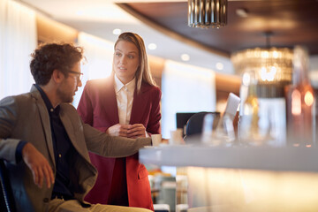 Young businesswoman talking to a young male colleague at coffee break at the bar. Business, people, bar