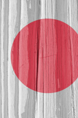 Fragment of Japan flag on a dry wooden surface, cracked with age. Light pale faded paint. Vertical...