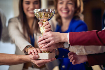 A group of cheerful business people celebrating the trophy at the hotel hallway. Hotel, business, people