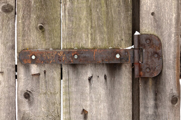 Ancient rusty hinge for the door on the background of an old wooden fence