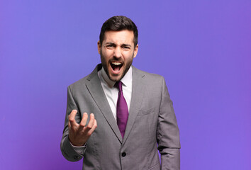 young adult handsome businessman looking angry, annoyed and frustrated screaming wtf or what’s...