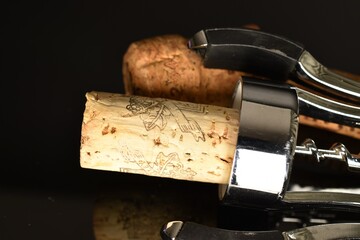 Several light brown, wine corks with a wine opener, close-up on a black background.