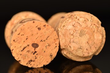 Two light brown, wine corks, close-up on a black background.