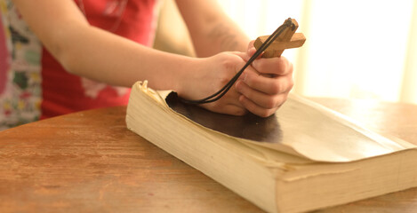 teenager girl praying to God holding a wooden cross,focus on cross.Concept of faith,hope and love