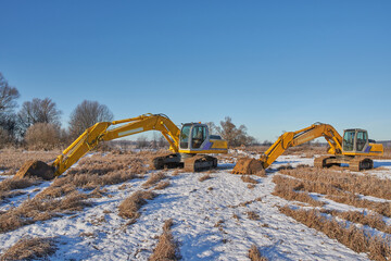 A pair of Excavator in the open air on a frosty winter day.