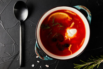 hodgepodge soup on black textured background with black spoon top view